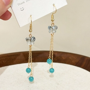 Close-up of golden butterfly fringe earrings with opal cat eye beads and tassels