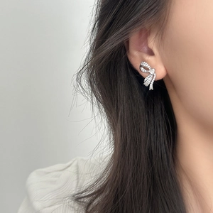Elegant silver bow stud earrings with sparkling crystals worn on a model's ear lobe