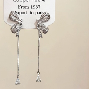 Close-up of zircon bow earrings with long tassels and silver finish in 100% copper