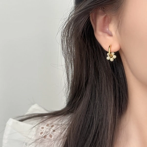 Elegant gold flower earrings with pavé zircon stones worn on model with white lace