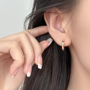 Geometric rose gold hoop earring with faceted surface and center sparkling zircon stone