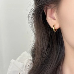 Golden geometric pleated hoop earring with sparkling zircon stone on a female model