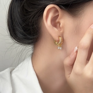 Gros plan de boucles d'oreilles dorées multicouches avec pendentif en zircon