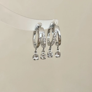 Détail de boucles d'oreilles double créoles argentées serties de zircons et cristaux