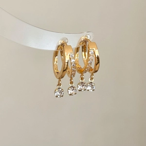 Détail de boucles d'oreilles créoles dorées à double rang avec oxydes de zirconium brillants