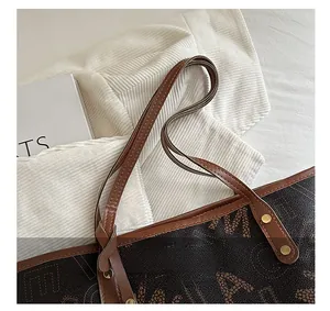 Detail of leather handles with gold studs on a brown printed tote shoulder bag