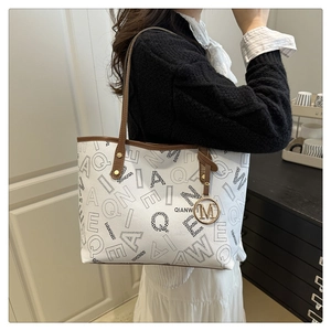 Detail view of the large capacity tote bag with letter print and gold M pendant