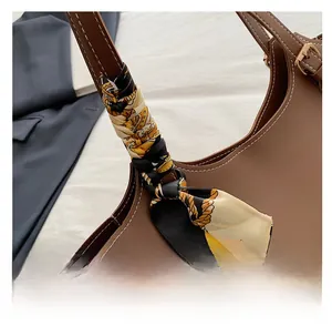 Detail showing high-quality brown leather tote with decorative patterned silk scarf handle