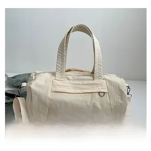 Detail of off-white nylon gym bag featuring durable handles and adjustable shoulder strap