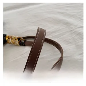 Detail of dark brown leather handle with white contrast stitching and silk scarf wrap