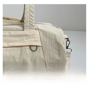 Detail view of off-white nylon travel bag showing textured fabric and metal hardware