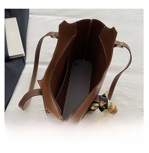 Interior view of large brown leather tote bag showing compartments and decorative scarf handle