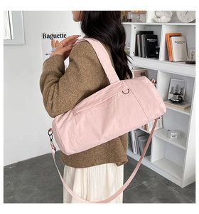 Close-up of light pink nylon gym bag with adjustable strap worn by a female model