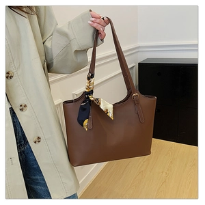 Close-up of brown tote bag side buckle and decorative printed silk scarf on handle