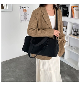 Lifestyle shot of large black nylon travel bag worn by model in a modern interior setting