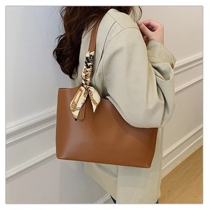 Detailed side view of large brown tote bag with decorative printed silk scarf handle