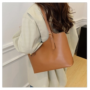 Detail of a large brown tote bag showing the adjustable shoulder strap and metal buckle