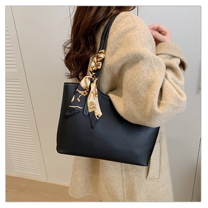 Detail of black leather tote bag with printed silk scarf handle shown on shoulder