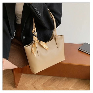 Detail of minimalist beige leather tote bag with decorative yellow printed handle scarf