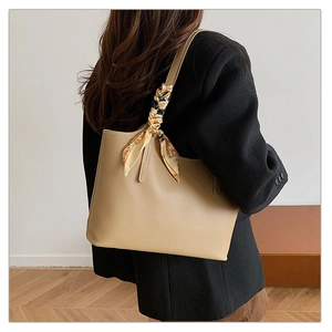 Detail of khaki tote bag with silk scarf on handle worn by model for office commuter style