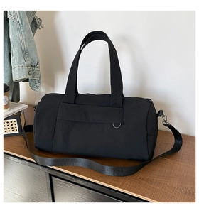 Detail of black nylon travel duffel bag with adjustable strap on a wooden table