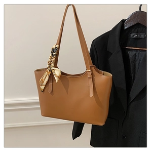 Detail of brown tote bag featuring a decorative silk scarf on the handle