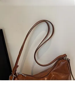 Detail of brown faux leather shoulder strap with silver metal buckle and zipper top