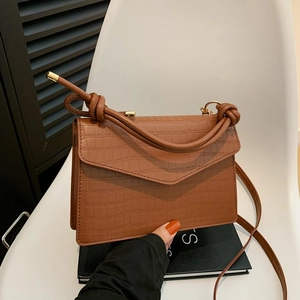 Brown crocodile textured crossbody bag with gold hardware and knotted rope strap
