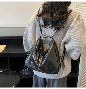 Rear view of black minimalist leather hobo bag showing versatile shoulder straps and texture