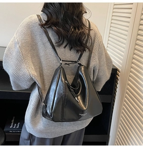 Close-up of black glossy PU leather tote bag showing smooth texture and stylish lettering