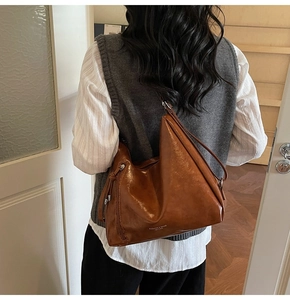 Detail of brown hobo bag in oil wax leather with side zipper and fringe pendant