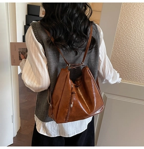 Rear view of model wearing a brown retro faux leather backpack with side metal zipper