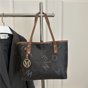 Brown printed tote bag with large capacity and golden metal pendant on a blazer