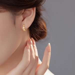 Boucles d'oreilles créoles fleurs marguerites dorées avec zircon portées par un mannequin