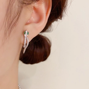 Boucles d'oreilles serpent en argent avec oxydes de zirconium et yeux verts sur modèle