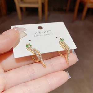Boucles d'oreilles serpent dorées avec zircons blancs sur carte de présentation