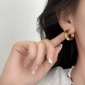 Minimalist gold hoop earrings with polished mirror finish worn on ear with chic outfit