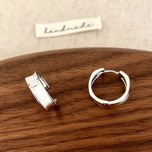 Close-up of minimalist S925 silver wide hoop earrings on dark walnut wood stand