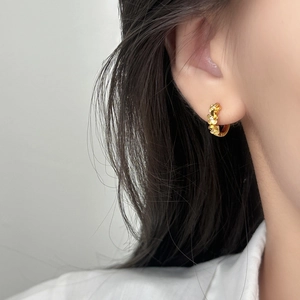 Élégantes créoles fleurs dorées avec zircons portées par un mannequin en vue latérale