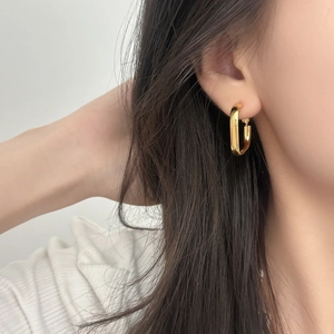 Boucles d'oreilles créoles géométriques dorées sur mannequin avec finition polie miroir