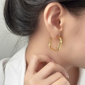 Boucles d'oreilles créoles dorées géométriques carrées portées par un modèle