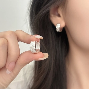 Silver koi scale hoop earrings shown on ear and held to highlight texture and design
