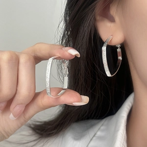 Silver square geometric earrings with textured matte finish shown on model's ear