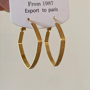 Detailed view of gold geometric hoop earrings with contrasting matte and polished textures