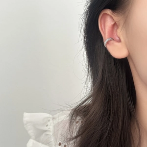 Close-up of a minimalist silver ear cuff set with pavé cubic zirconia on ear cartilage