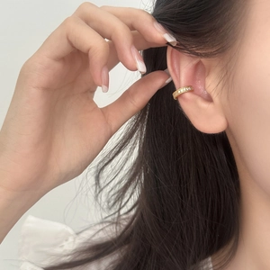 Close-up of a gold-plated ear cuff with white cubic zirconia worn on the ear cartilage