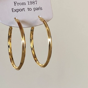 Macro view of large gold hoop earrings with faceted diamond-cut texture on display card