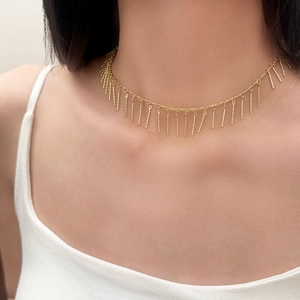 Détail d'un collier ras du cou doré à franges métalliques porté par un mannequin