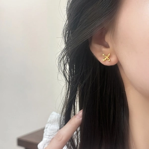 Minimalist gold-plated X-shaped flower stud earrings shown on model for elegant look