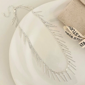 Détail d'un collier à franges argentées avec pampilles texturées et fermoir mousqueton